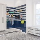 Custom garage with two-tone high-gloss cabinetry, slat wall organization, and brushed aluminum accents