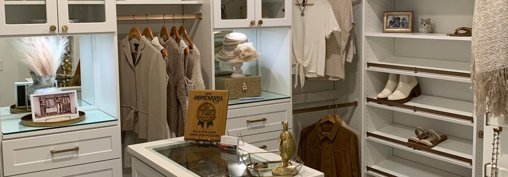 Bright white walk-in closet with gold hardware, built-in drawers, glass displays, and organized hanging sections