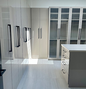 Custom walk-in closet with Island with pull-out accessory drawers and glass doors
