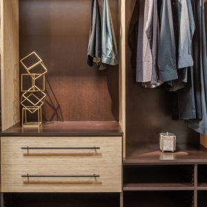 Reach-in closet in Summer Breeze with Cocoa backing. Includes open shelving, cubbies for folded clothing, and drawers with long matte black bar pulls.