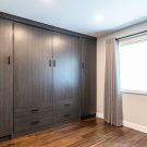 Custom wall bed in concealed dark melamine cabinetry