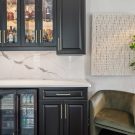 Wet bar with custom black cabinetry and glass doors