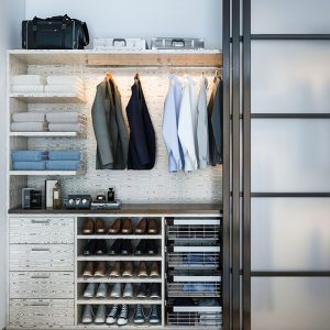 Modern reach-in closet with glass-front doors, spotlight-lit shelving, and a mix of hanging sections and drawer storage.