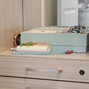 Jewelry box with assorted bracelets, pearls, and necklaces displayed on a built-in closet drawer surface.