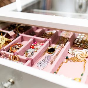 Jewelry drawer with velvet-lined compartments and a glass top integrated into a custom island unit.
