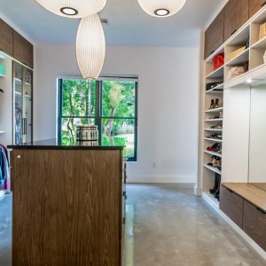 Custom closet with white and walnut tones, featuring teal pull-out fabric bins, a full-length mirror, and dedicated shoe cubbies.