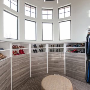Circular walk-in closet with modern gray drawers lining the curved walls, topped with open shoe shelving