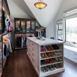 Stylish walk-in closet with black-framed glass cabinetry, island with shoe shelving
