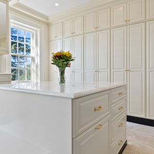 Luxurious white closet with gold hardware and wall-to-wall custom cabinetry