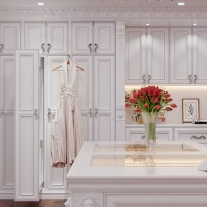 Elegant white walk-in closet with ornate cabinetry, a center island, and classic molding