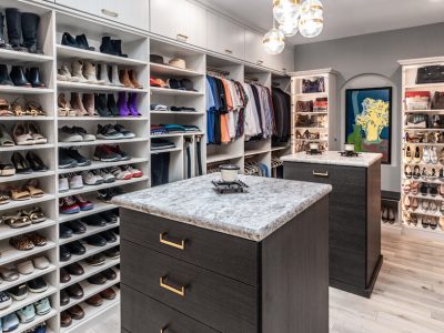 Spacious walk-in closet with white shelving, brown cabinetry, and extensive shoe storage, styled with neutral tones.