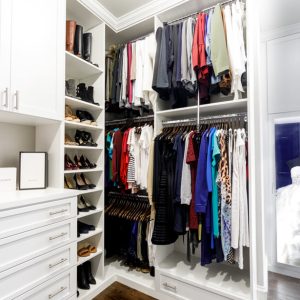Custom walk-in with shaker cabinetry, full-extension drawers, and crown molding. Includes angled shoe shelves, double-hang sections, and a lit display niche for special garments.