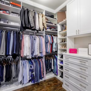 Custom walk-in closet with white soft-close drawers and cabinetry, open shoe shelves, and organizers