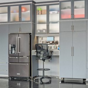 Gray garage built-in setup with an integrated refrigerator, tool workstation, and high cabinets for concealed storage.