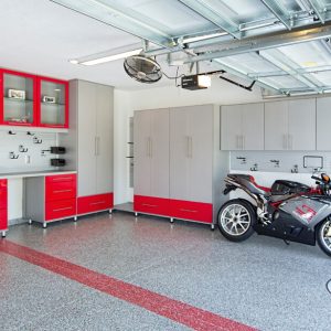 Garage with gray cabinets and glossy red drawers, slatwall organizer system, heavy-duty hooks, and epoxy flooring