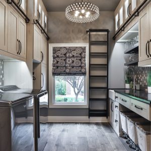 Custom laundry room with ladder for high reach items and fabric rolling laundry bins