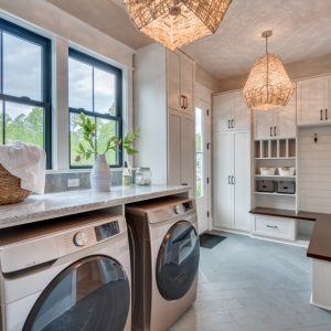 Custom laundry room and mudroom with folding station, built-in bench, coat hooks, and white shaker cabinetry.