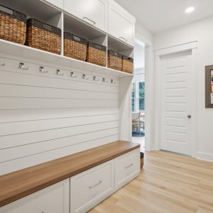 Custom entryway mudroom with coat hooks. shiplap, and built-in bench