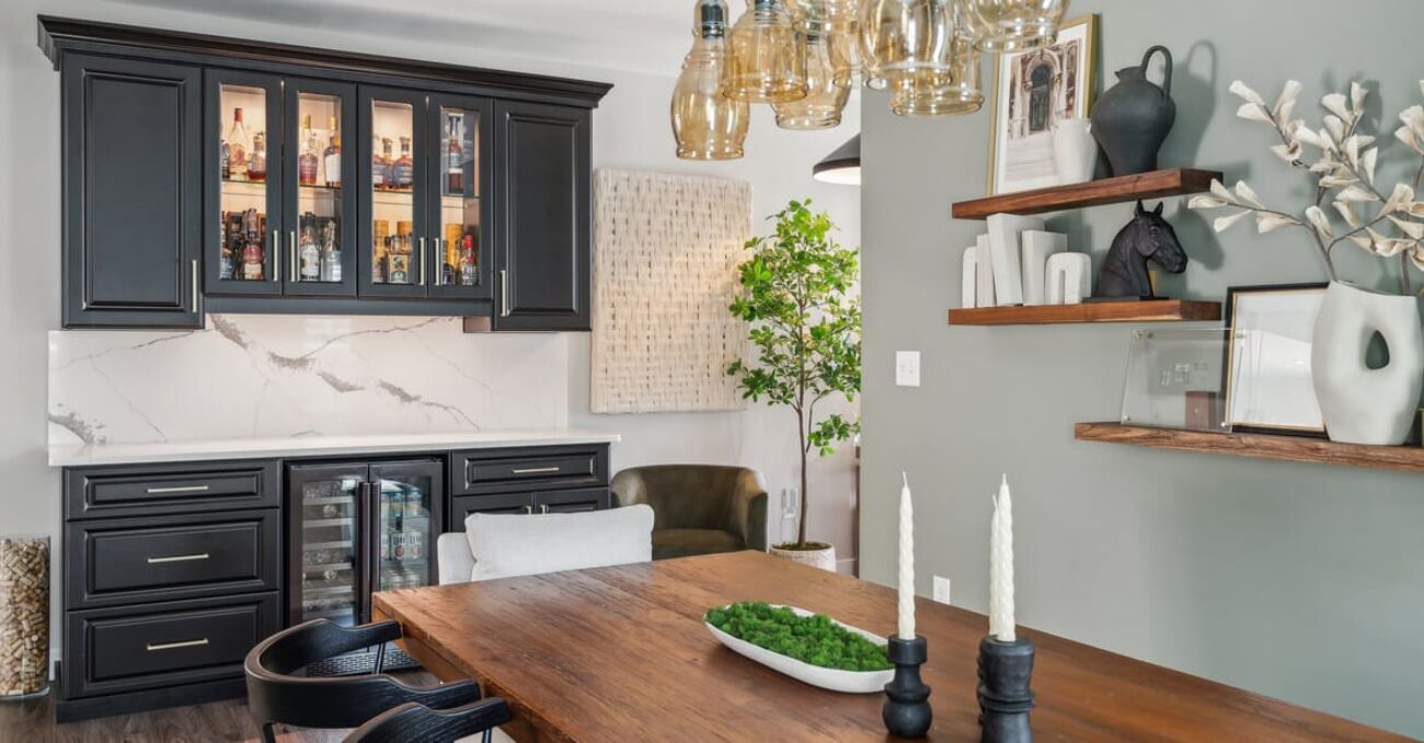 Sophisticated bar design in a dining space with glass-front black cabinets, white marble backsplash, dual beverage coolers, and decorative shelving.