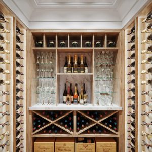 Premium wine cellar featuring wall-mounted bottle racks, central tasting area with glass shelving, X-style wine cubbies, and ambient lighting.