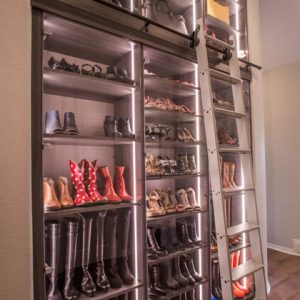Custom shoe shelving display with glass fronts and LED lighting strips, accompanied by rolling ladder for access to high shelves