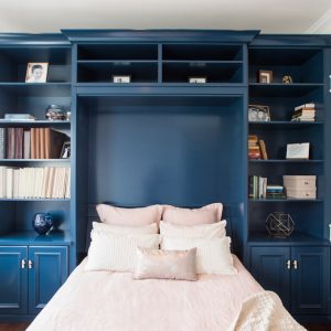 Custom wall bed cabinetry in navy blue with built-in bookshelves