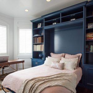 Navy blue built-in wall bed with surrounding bookcases and upper storage