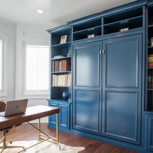 Custom wall bed cabinetry in navy blue with built-in bookshelves and concealed bed