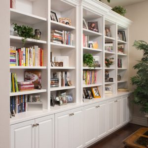 White built-in wall unit with open shelving and lower cabinets with crown molding