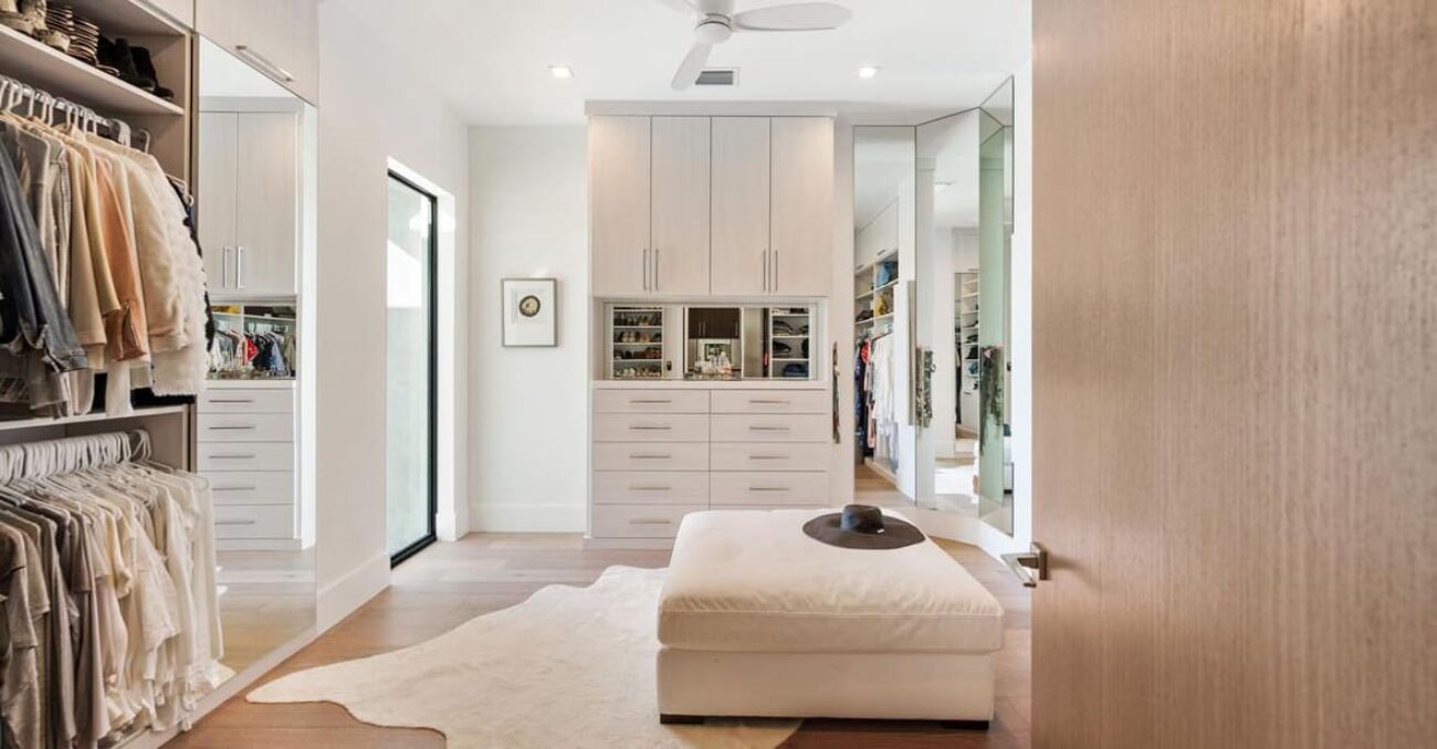 Contemporary wardrobe closet with slab front cabinet doors and drawers. The central built-in unit features mirrored cubbies with velvet-lined necklace organizers.