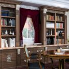Traditional library built-ins with ornate trim and crown molding, carved corbels, and inset panel doors.