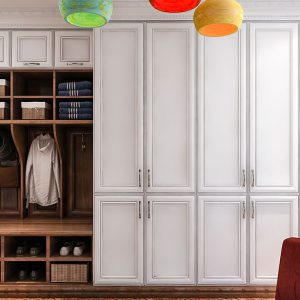 Mudroom wall unit with full height concealed storage cabinets, built-in bench, coat hooks, and shoe shelving.