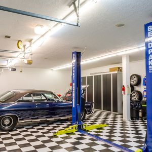 Stylized garage system with black melamine cabinetry, open shelving, and slatwall organizer.