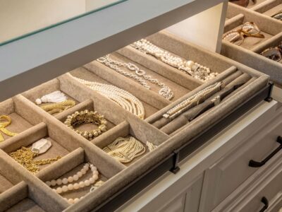 Close-up of a custom velvet-lined jewelry drawer and a separate sunglass organizer inside a white closet island.